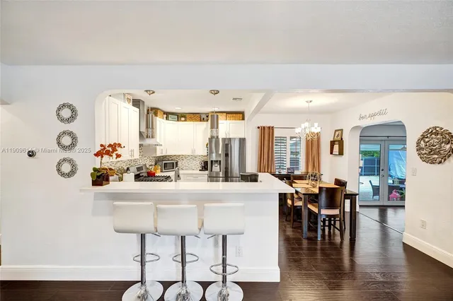 a kitchen with a stove a sink dishwasher a dining table and chairs with wooden floor