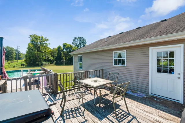 a patio with table and chairs and potted plants with wooden floor and fence