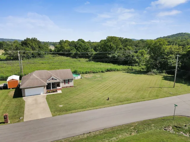 a view of a lake with lawn chairs next to a yard