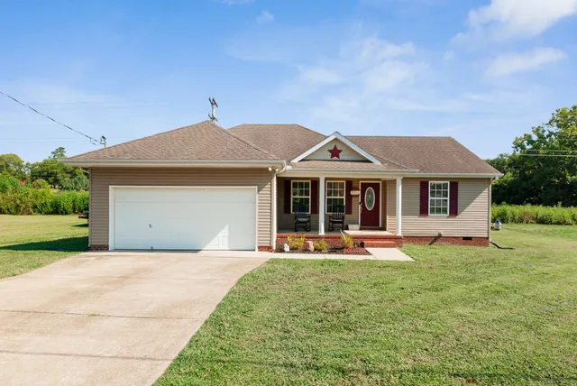 a front view of a house with a garden and trees
