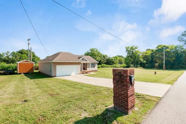 a front view of house with yard and trees in the background