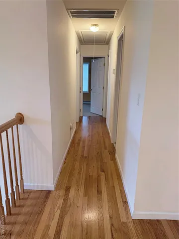 a view of an empty room with wooden floor and stairs