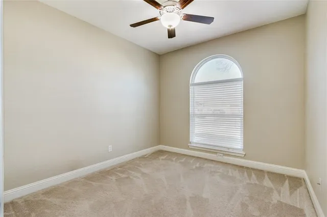 an empty room with windows and ceiling fan
