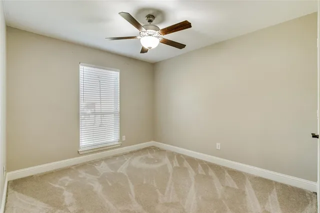 an empty room with a window and a ceiling fan