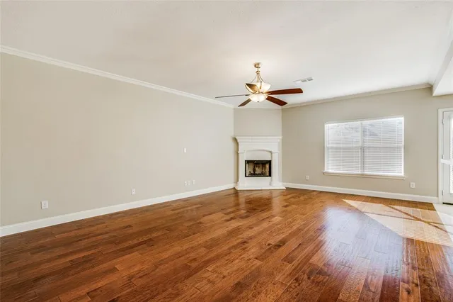 a view of an empty room with wooden floor fireplace and a window