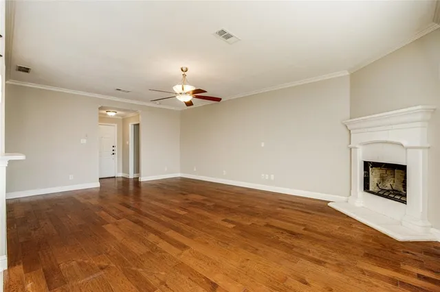 a view of an empty room with wooden floor fireplace and a window