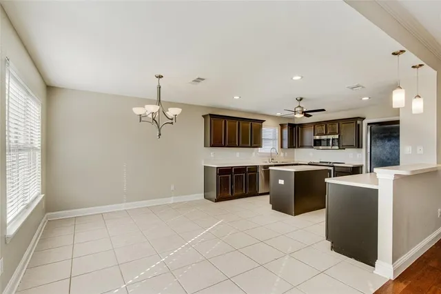 a kitchen with stainless steel appliances granite countertop a refrigerator a sink a stove top oven and a dishwasher next to a window