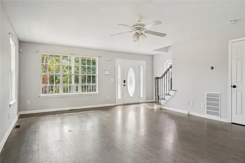 a view of an empty room with a window and wooden floor