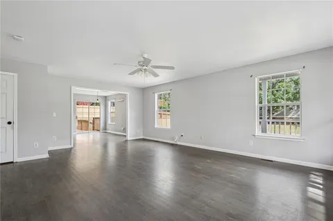 a view of an empty room with a window and wooden floor