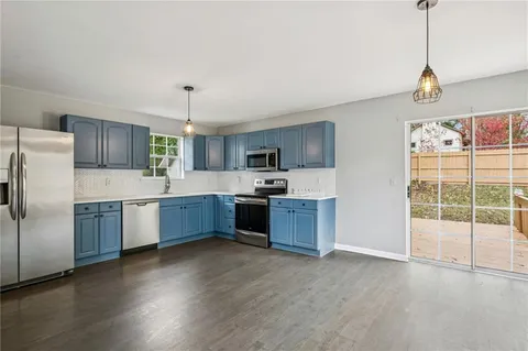 a large kitchen with stainless steel appliances granite countertop a stove a sink dishwasher a refrigerator and a wooden floor with granite countertops