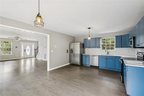 a open kitchen with a refrigerator a sink dishwasher a dining table and chairs with wooden floor