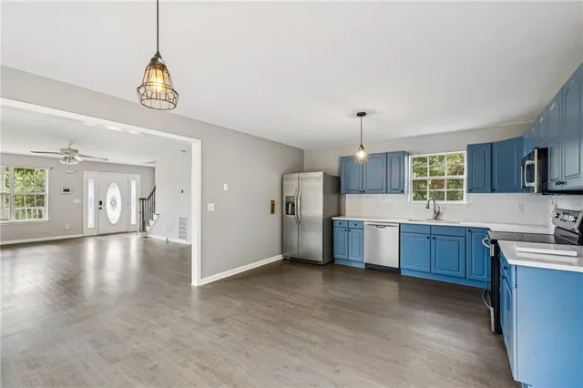 a open kitchen with a refrigerator a sink dishwasher a dining table and chairs with wooden floor