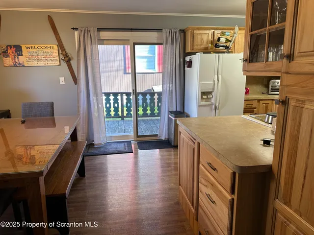 a kitchen with stainless steel appliances granite countertop a refrigerator a stove and a dining table with wooden floor