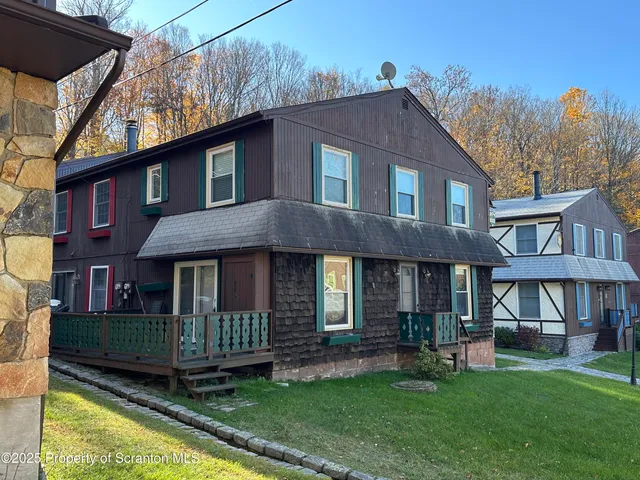 a view of a brick house with a yard plants and large trees