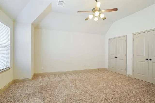 an empty room with a chandelier fan and closet area