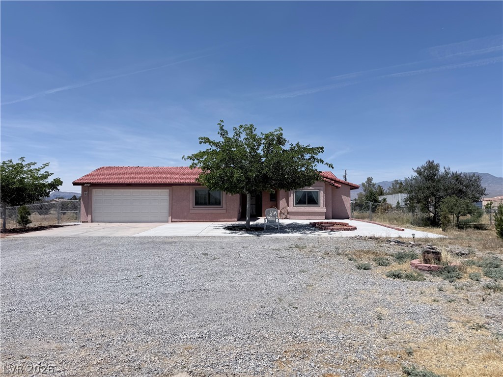 1220 East Gamebird Road Pahrump, NV 89048 - Photo 30 of 49 A terracotta-tiled roof crowns this home, with a spacious gravel lot and mountain backdrop.
