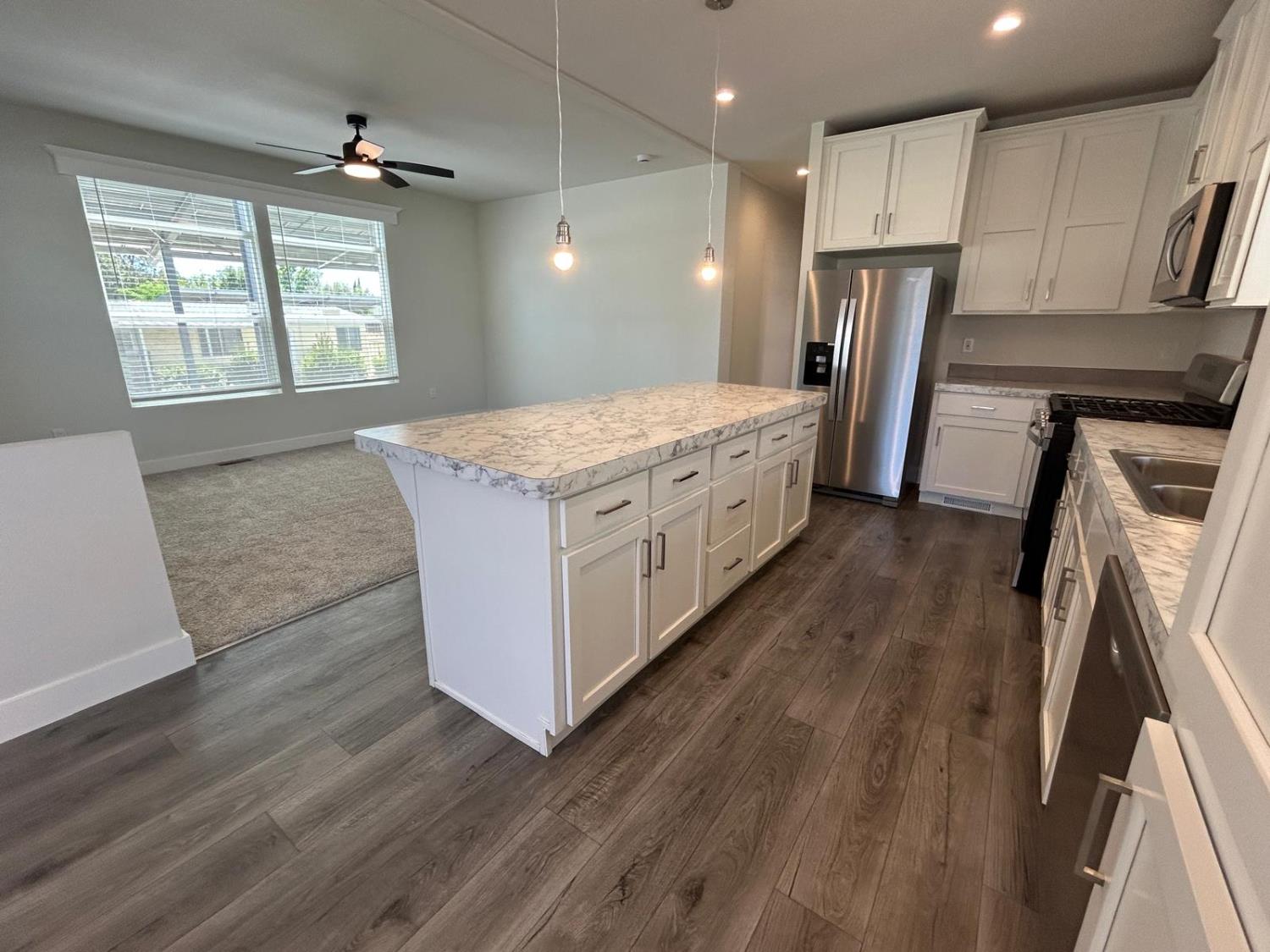 9060 Auburn Folsom Road, Unit 25 Granite Bay, CA 95746 - Photo 10 of 29 a kitchen with stainless steel appliances granite countertop a refrigerator a sink dishwasher a stove and white countertops with wooden floor