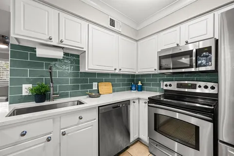 a kitchen with granite countertop white cabinets stainless steel appliances and a counter space