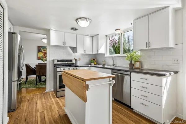 a dining room with furniture a wooden floor and a kitchen view