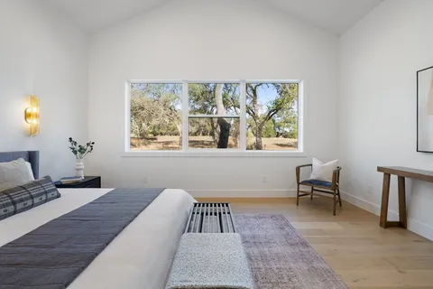a bedroom with a bed a table and chair with a large windows