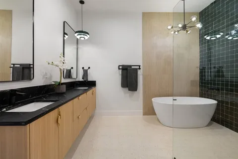 a bathroom with a double vanity sink a toilet a mirror and bathtub