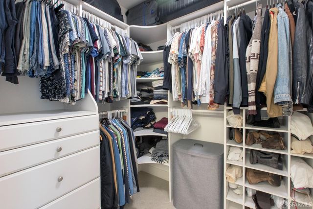 a view of walk in closet with clothes and shoes
