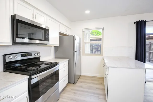 a kitchen with granite countertop a refrigerator and a stove top oven