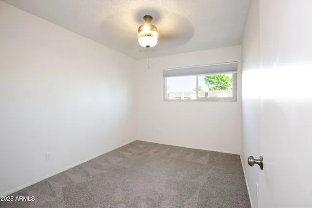 an empty room with fan and windows