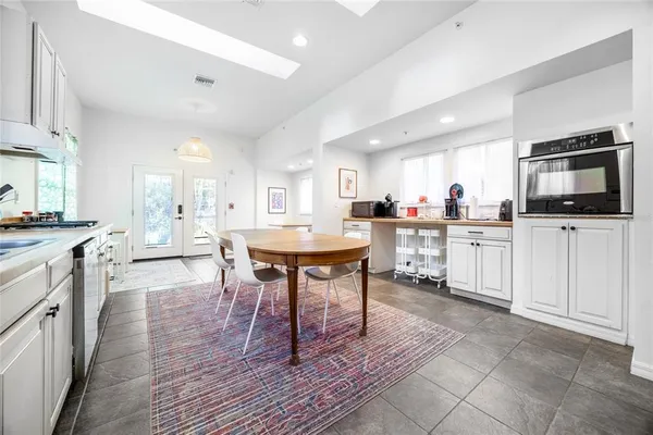 a kitchen with stainless steel appliances kitchen island granite countertop a table chairs sink and cabinets