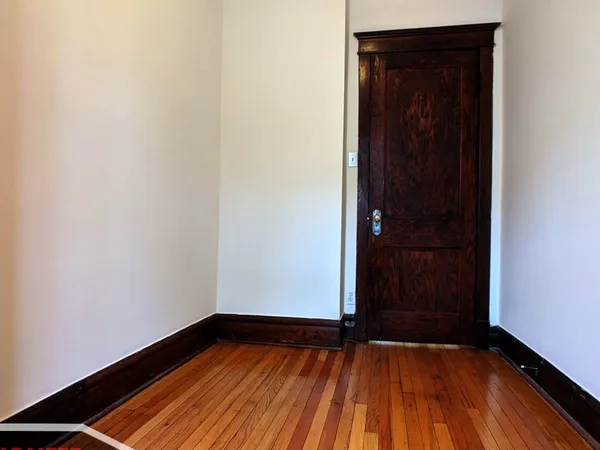 a view of an empty room with closet and wooden floor