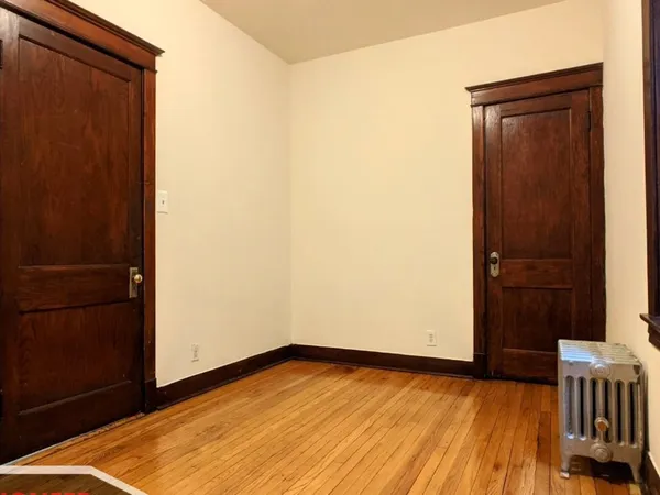 a view of an empty room with wooden floor and a door