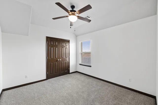 an empty room with a ceiling fan and a window