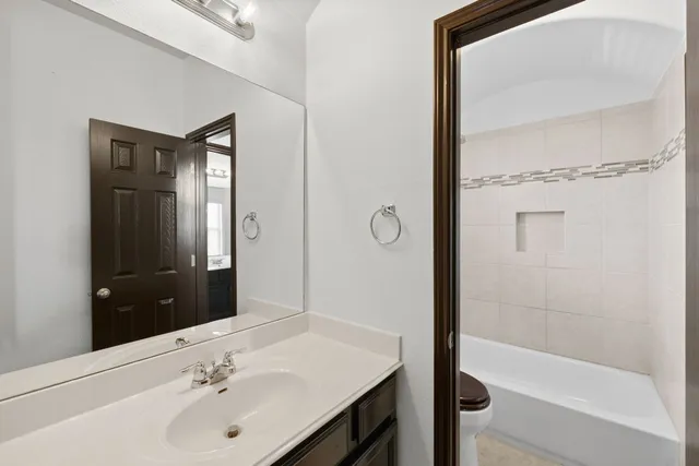 a bathroom with a bathtub shower sink vanity and mirror