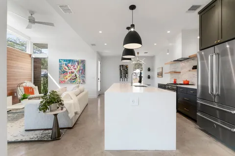 a kitchen with stainless steel appliances kitchen island granite countertop a refrigerator a sink a stove and a wooden floors