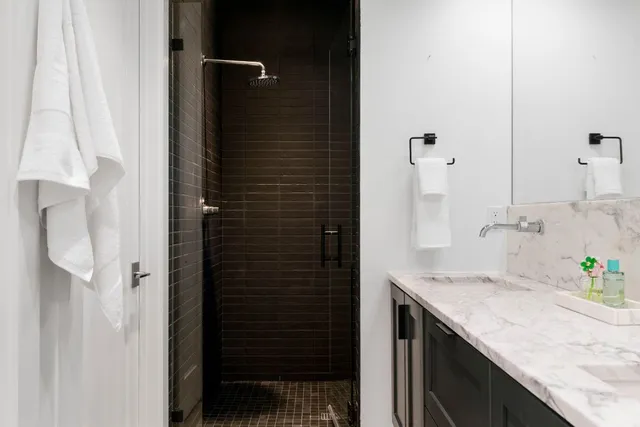 a bathroom with a granite countertop shower a sink and a mirror