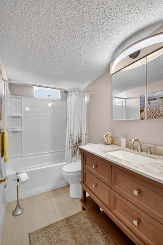 a bathroom with a granite countertop sink toilet a mirror and bathtub