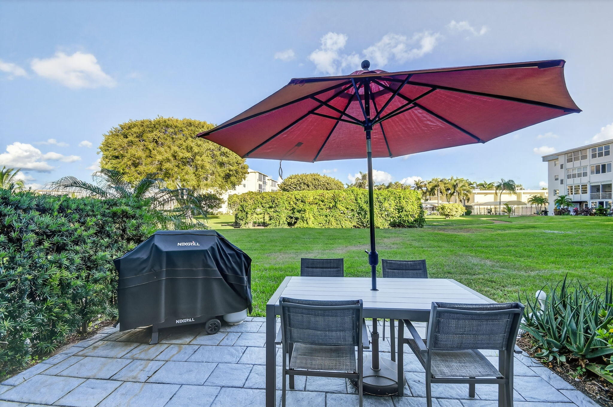 2400 Northeast 1st Lane, Unit 102 Boynton Beach, FL 33435 - Photo 29 of 44 a view of a deck with a table and chairs under an umbrella