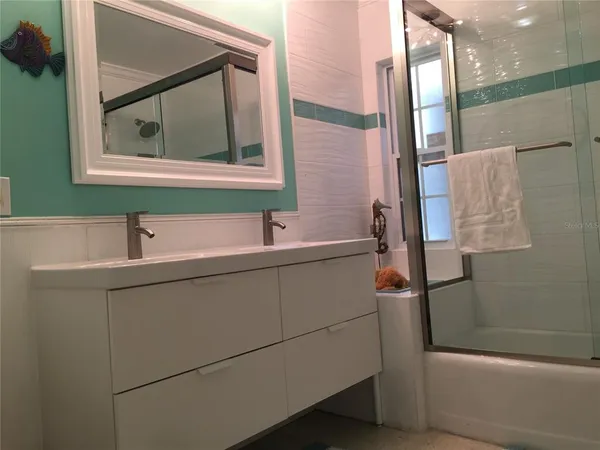 a bathroom with a sink and mirror with bathtub