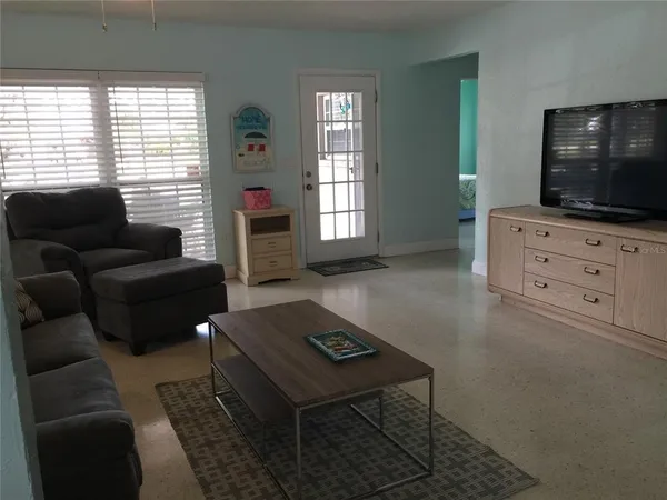 a living room with furniture a flat screen tv and a window