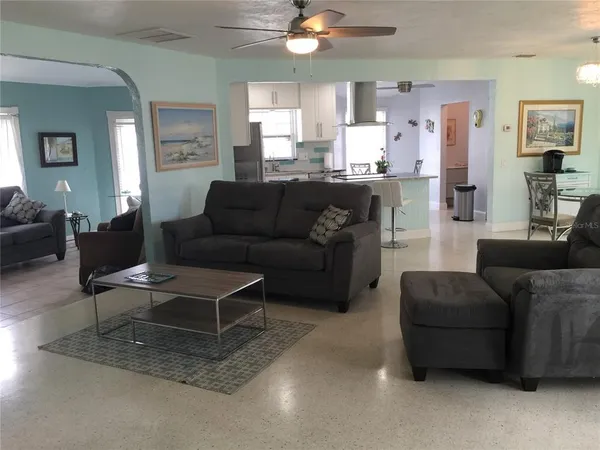a living room with furniture and a dining table with kitchen view
