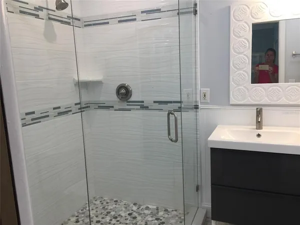 a bathroom with a shower sink and mirror