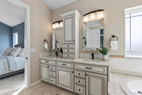 a spacious bathroom with double vanity a mirror a lamp and a bathtub