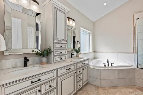 a bathroom with double vanity sinks a mirror and a bathtub