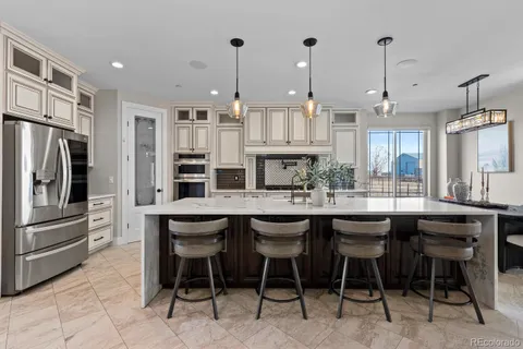 a kitchen with stainless steel appliances granite countertop a table chairs sink and cabinets