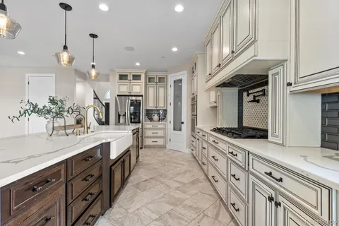 a large kitchen with granite countertop a large stove top oven a sink a counter space and cabinets