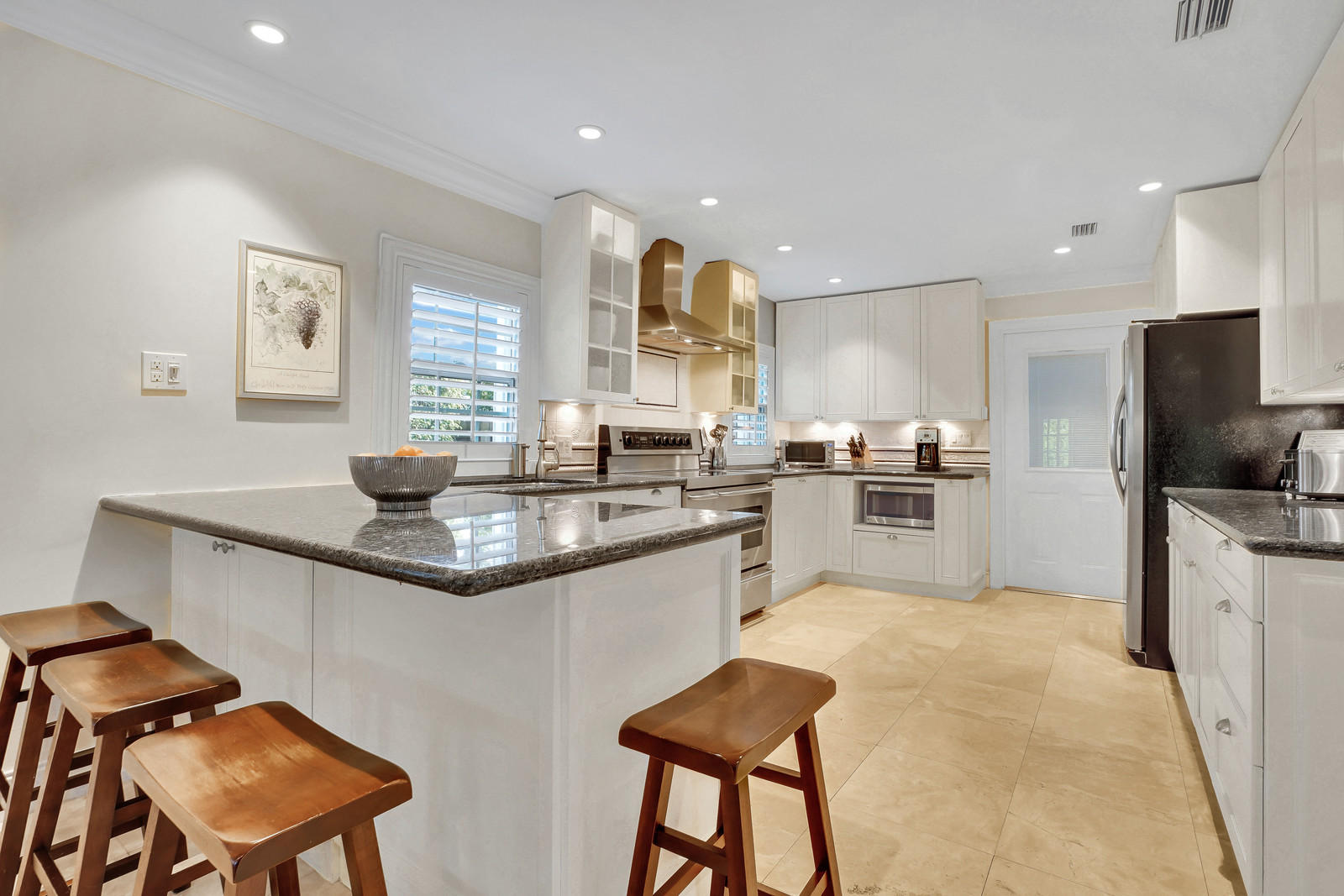 979 Southwest 18th Street Boca Raton, FL 33486 - Photo 12 of 30 a kitchen with stainless steel appliances granite countertop a sink a stove a refrigerator cabinets and a dining table with wooden floor