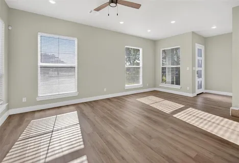 an empty room with wooden floor and windows