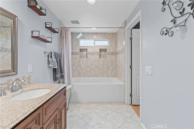 a bathroom with a granite countertop sink a mirror and a bathtub