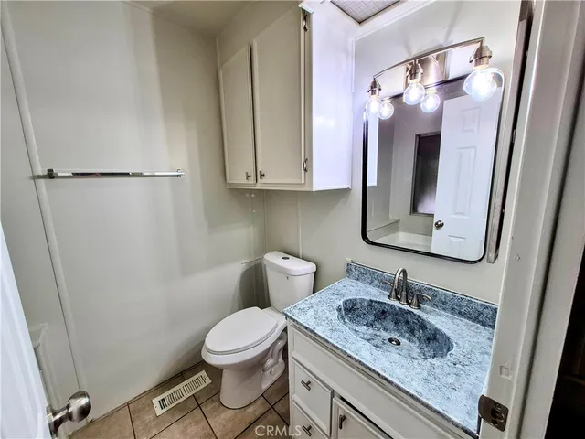 a bathroom with a granite countertop sink toilet and mirror