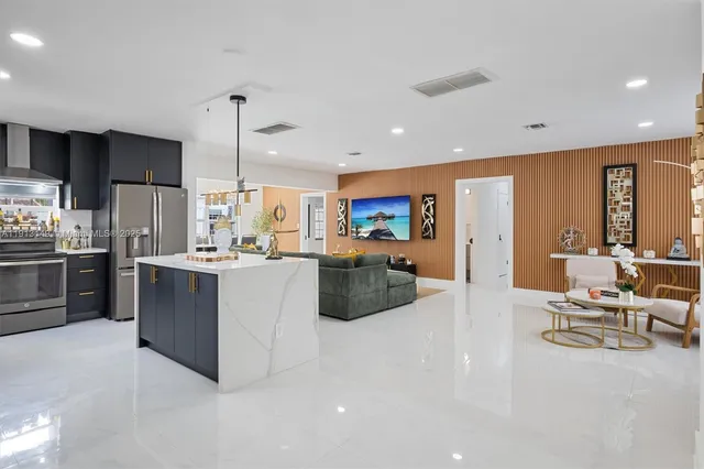 a kitchen with stainless steel appliances kitchen island granite countertop a refrigerator and a sink